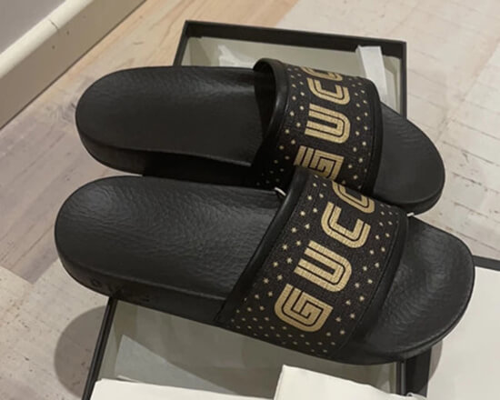 Gucci black leather slides with the iconic gold-toned GUCCI writing.