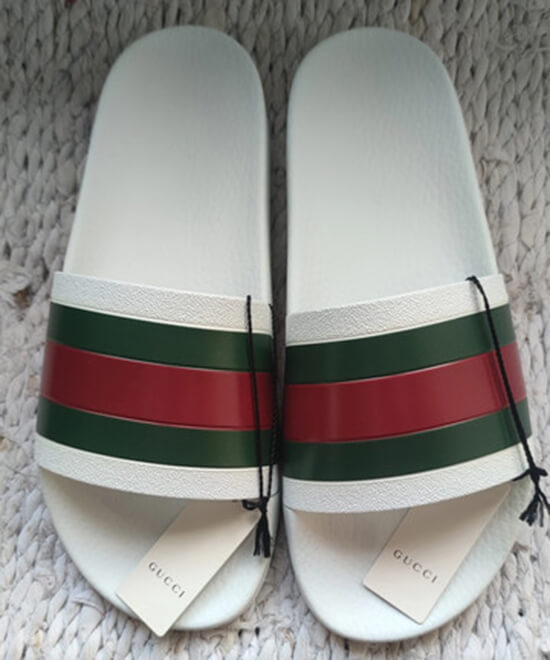 Stylish white Gucci slides featuring the classic green and red web stripe on the strap.